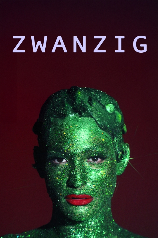 Zwanzig Das Bild zeigt die Großaufnahme einer Person, deren Gesicht vollständig mit grüner Glitzerfarbe übergeschminkt ist. Ihr intensiver Blick ist direkt in die Kamera gerichtet. Knallroter Lippenstift kontrastiert mit der grünen Haut. Der Hintergrund ist schwarzrot. Am oberen Rand des Bildes steht in lila Kleinbuchstaben in schnörkelloser Schrift das Wort „ZWANZIG“.